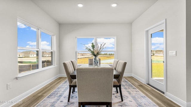 dining area with wood-type flooring, a water view, and a healthy amount of sunlight