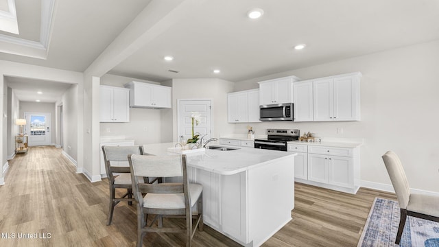 kitchen with an island with sink, appliances with stainless steel finishes, and white cabinets