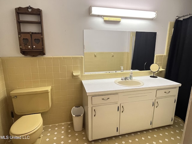 bathroom featuring vanity, tile walls, and toilet