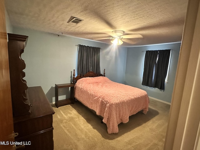 carpeted bedroom with ceiling fan and a textured ceiling