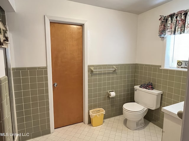 bathroom with tile patterned flooring, vanity, toilet, and tile walls