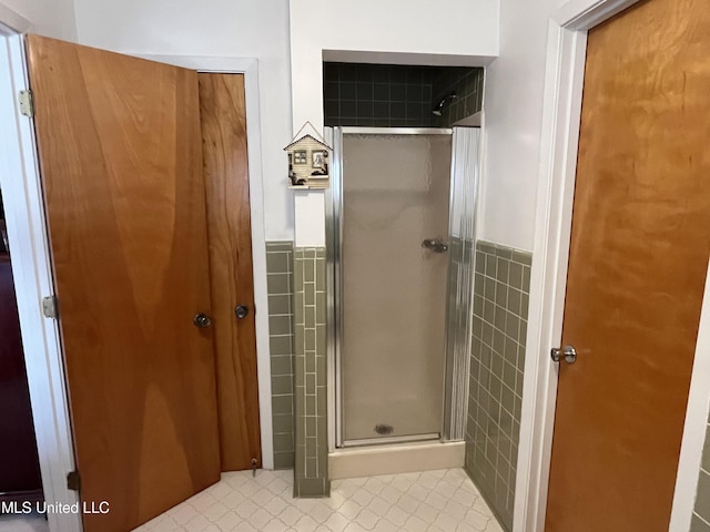 bathroom with a shower with shower door and tile walls