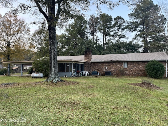 exterior space with a sunroom, central AC unit, and a yard