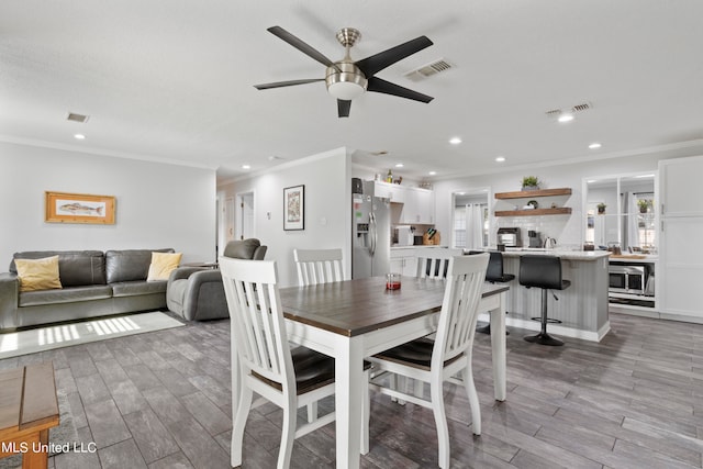 dining room featuring crown molding, light wood-type flooring, and ceiling fan