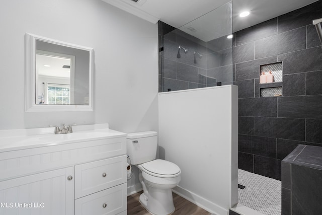 bathroom featuring vanity, tiled shower, hardwood / wood-style flooring, and toilet