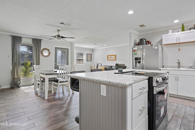 kitchen featuring appliances with stainless steel finishes, sink, a kitchen island, white cabinetry, and ceiling fan