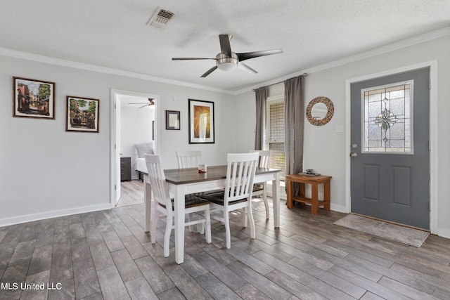 dining area featuring crown molding, hardwood / wood-style flooring, a textured ceiling, and ceiling fan