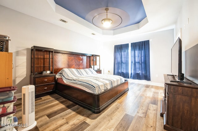 10053 Kingston Rd, Bay Saint Louis, MS 39520 - bedroom with a tray ceiling, light wood-type flooring, and baseboards