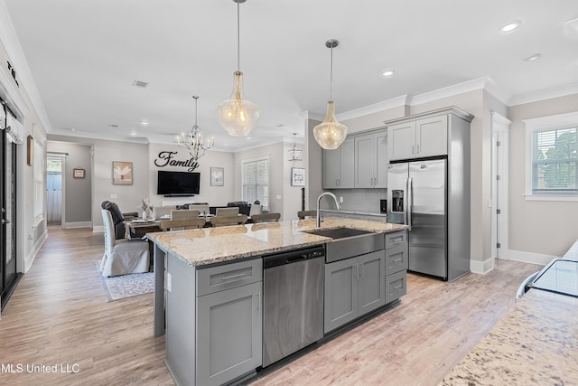 kitchen featuring light stone countertops, appliances with stainless steel finishes, a sink, and gray cabinetry