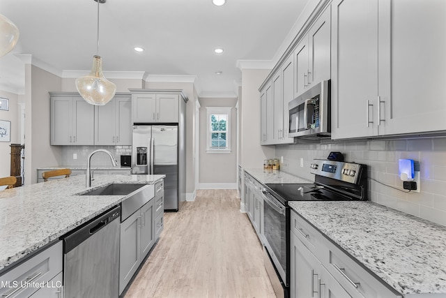 kitchen with appliances with stainless steel finishes, a sink, gray cabinetry, and light stone countertops