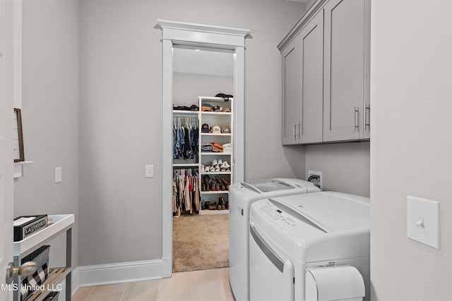 clothes washing area featuring light tile patterned floors, light colored carpet, separate washer and dryer, baseboards, and cabinet space