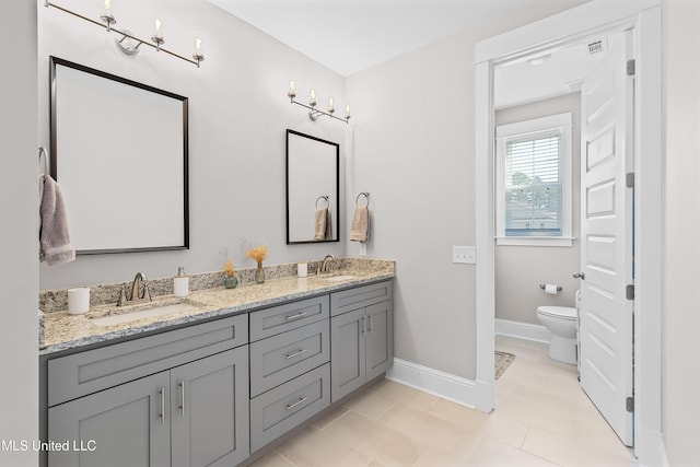 full bathroom with double vanity, a sink, toilet, and baseboards