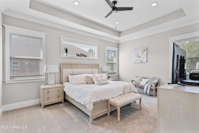 bedroom featuring a raised ceiling, light colored carpet, baseboards, and multiple windows