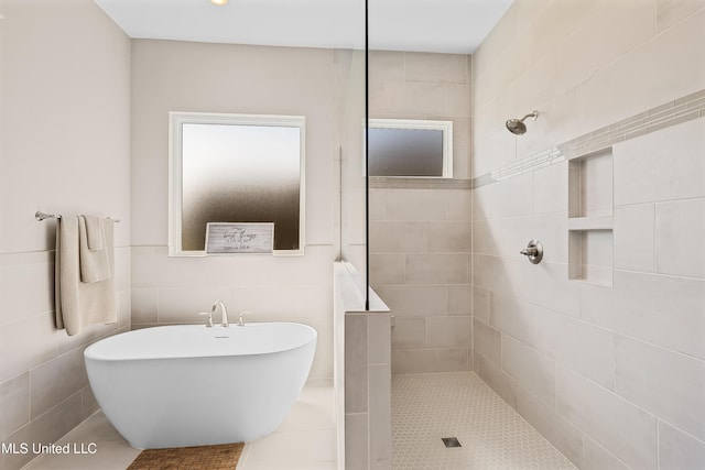 bathroom with a walk in shower, a freestanding bath, and tile walls