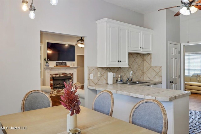 kitchen featuring a sink, ceiling fan, tasteful backsplash, and white cabinets