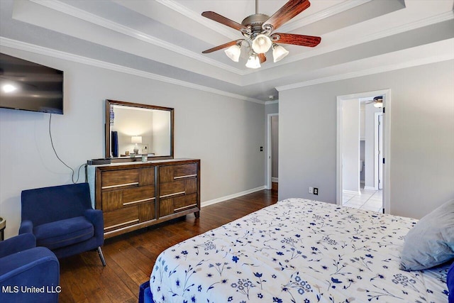 bedroom featuring crown molding, baseboards, a raised ceiling, hardwood / wood-style flooring, and a ceiling fan