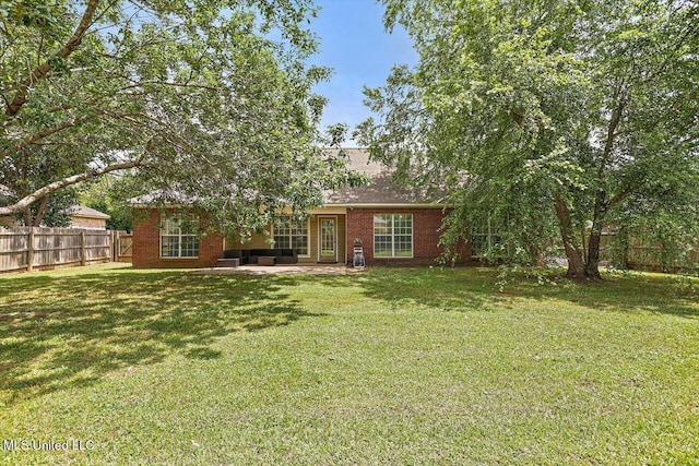 rear view of property featuring a yard, brick siding, and fence