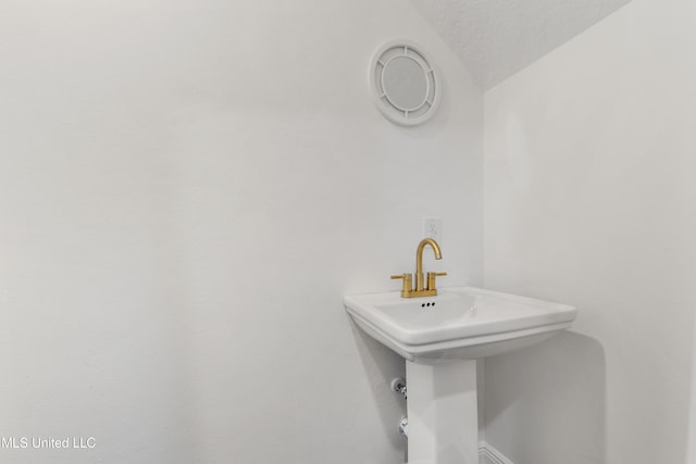 bathroom featuring a textured ceiling and vaulted ceiling