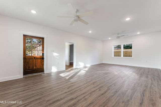 unfurnished living room featuring a wealth of natural light, dark wood-type flooring, and ceiling fan