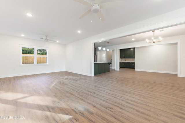 unfurnished living room with hardwood / wood-style flooring and ceiling fan with notable chandelier