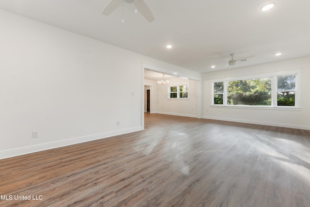 unfurnished living room featuring hardwood / wood-style flooring and ceiling fan with notable chandelier