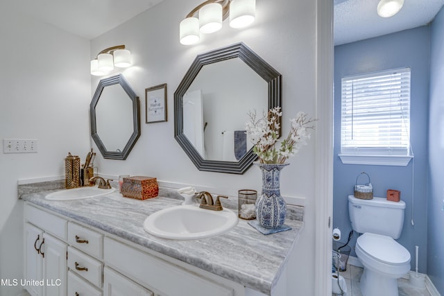 full bathroom with a sink, toilet, and double vanity