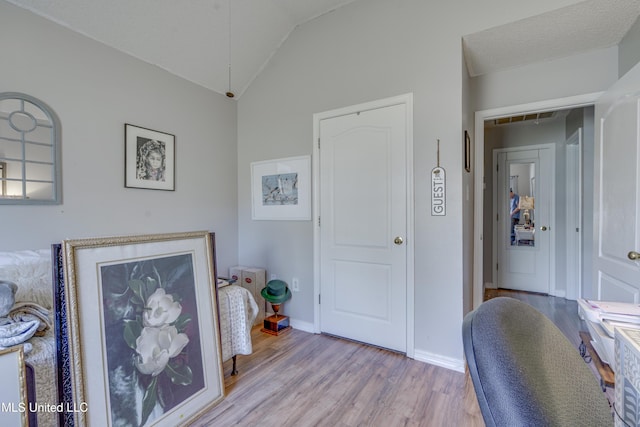 office space featuring lofted ceiling, light wood-style floors, baseboards, and a textured ceiling