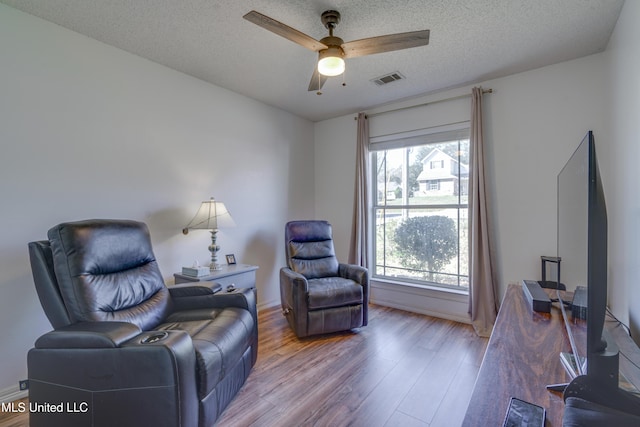 sitting room featuring a wealth of natural light, ceiling fan, a textured ceiling, and wood finished floors