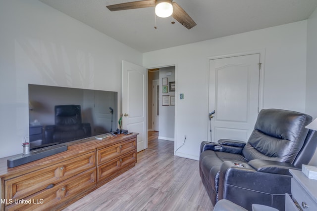 living area featuring a ceiling fan, light wood-type flooring, and baseboards