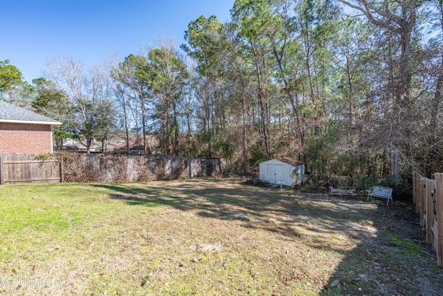 view of yard featuring a storage shed, a fenced backyard, and an outbuilding