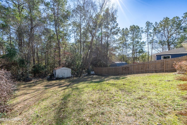 view of yard featuring fence, an outdoor structure, and a storage unit