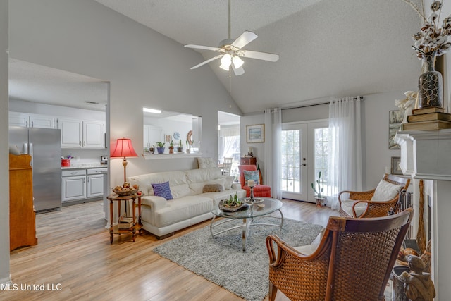 living room featuring a textured ceiling, high vaulted ceiling, french doors, and light wood-style floors