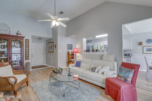 living room with high vaulted ceiling, light wood-type flooring, visible vents, and ceiling fan