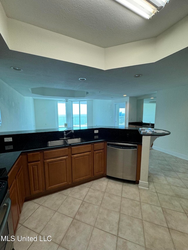 kitchen with kitchen peninsula, sink, light tile patterned flooring, stainless steel dishwasher, and a textured ceiling