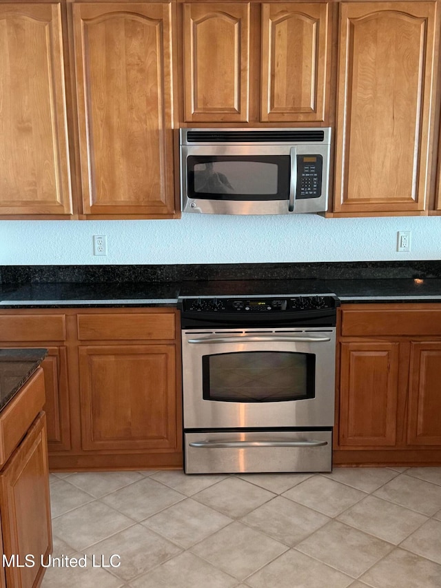 kitchen with appliances with stainless steel finishes and dark stone countertops