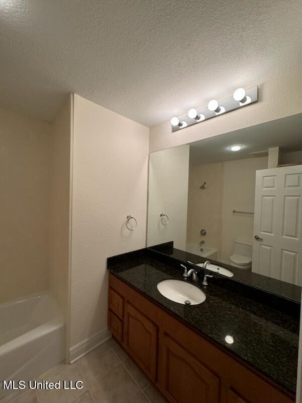 full bathroom with a textured ceiling, toilet, shower / tub combination, vanity, and tile patterned flooring