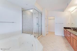 bathroom with a whirlpool tub, vanity, tile patterned flooring, and a stall shower