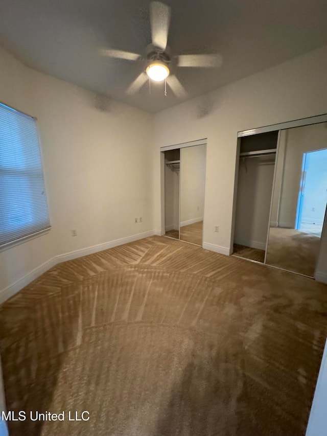 unfurnished bedroom featuring ceiling fan, multiple closets, and carpet