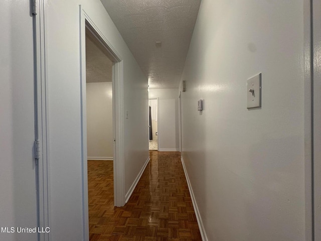 hall with baseboards and a textured ceiling