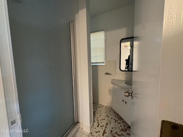 bathroom featuring tile patterned floors, a wainscoted wall, a stall shower, tile walls, and vanity