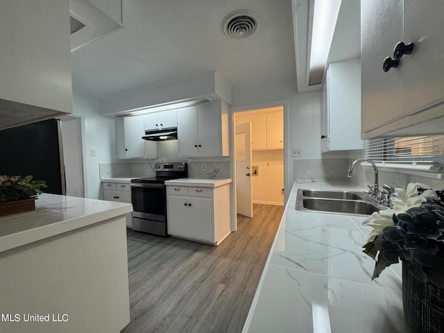 kitchen featuring visible vents, a sink, under cabinet range hood, backsplash, and stainless steel range with electric cooktop