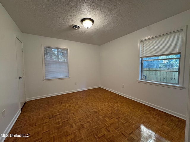 spare room featuring visible vents, a textured ceiling, and baseboards