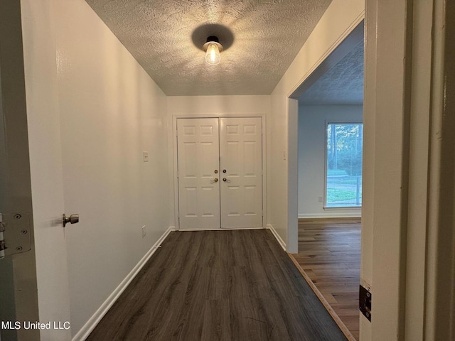 interior space with dark wood finished floors, a textured ceiling, and baseboards