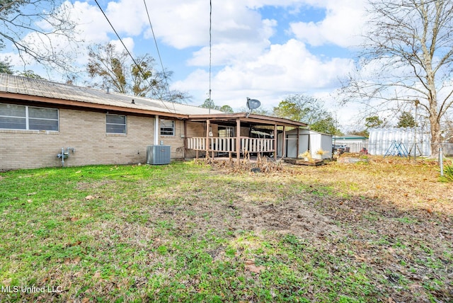 back of house with central AC, a storage shed, and a lawn