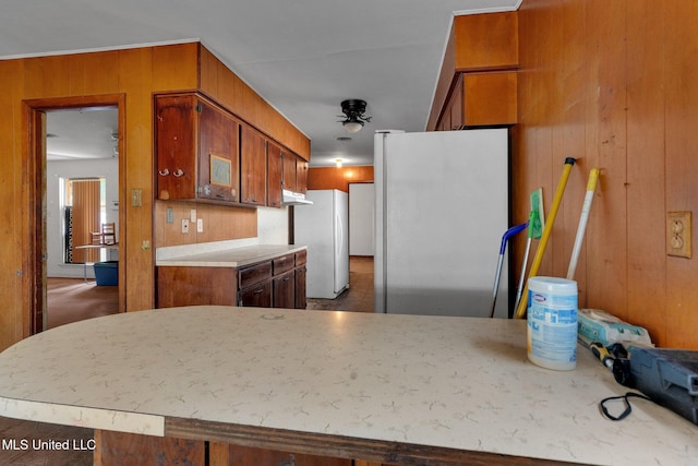 kitchen featuring wooden walls, fridge, kitchen peninsula, and white fridge