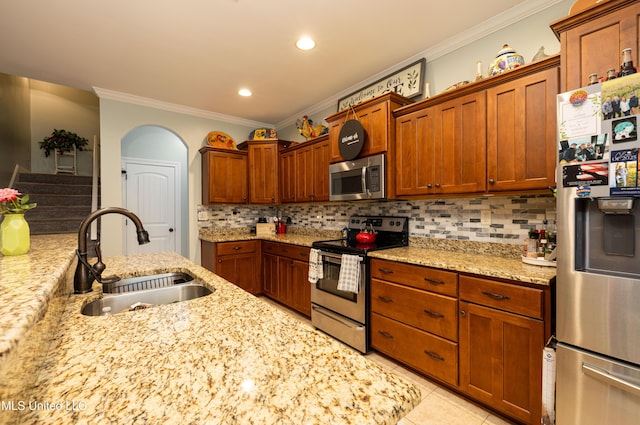 1668 Farindale Cv, Nesbit, MS 38651 - kitchen with appliances with stainless steel finishes, ornamental molding, decorative backsplash, light stone countertops, and brown cabinetry
