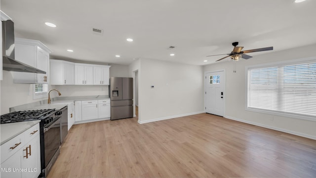 kitchen featuring a sink, visible vents, stainless steel refrigerator with ice dispenser, wall chimney exhaust hood, and gas range