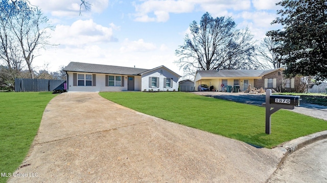 ranch-style home featuring driveway, fence, and a front yard