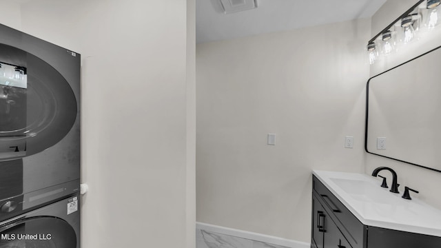 washroom featuring marble finish floor, visible vents, stacked washer / dryer, a sink, and baseboards