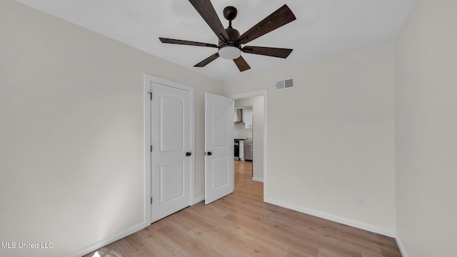 unfurnished bedroom featuring a ceiling fan, visible vents, light wood finished floors, and baseboards